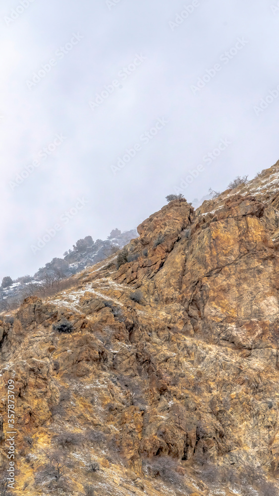 Vertical crop Snow dusted terrain of the rocky Prvo Canyon in Utah with cloudy sky background Vertical crop Snow dusted terrain of the rocky Prvo Canyon in Utah with cloudy sky background