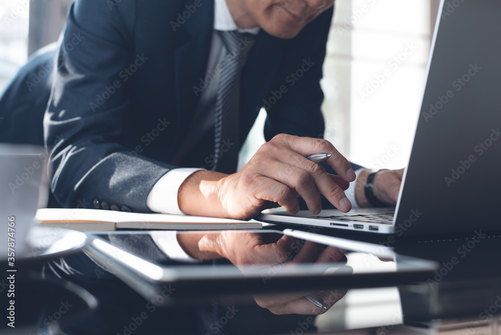 Obraz premium Asian businessman surfing internet working on laptop computer in modern office