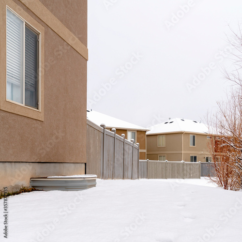 Square Ground blanketed with snow in front of houses and woodne fence in winter photo