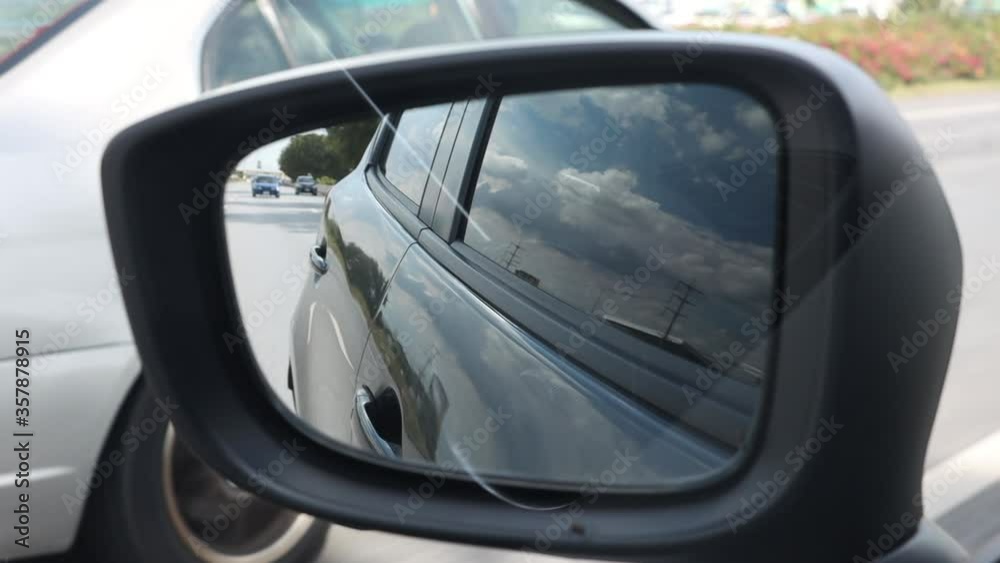 A Looking in the rearview mirror while driving on the highway. A Looking in the rearview mirror while driving on the highway.