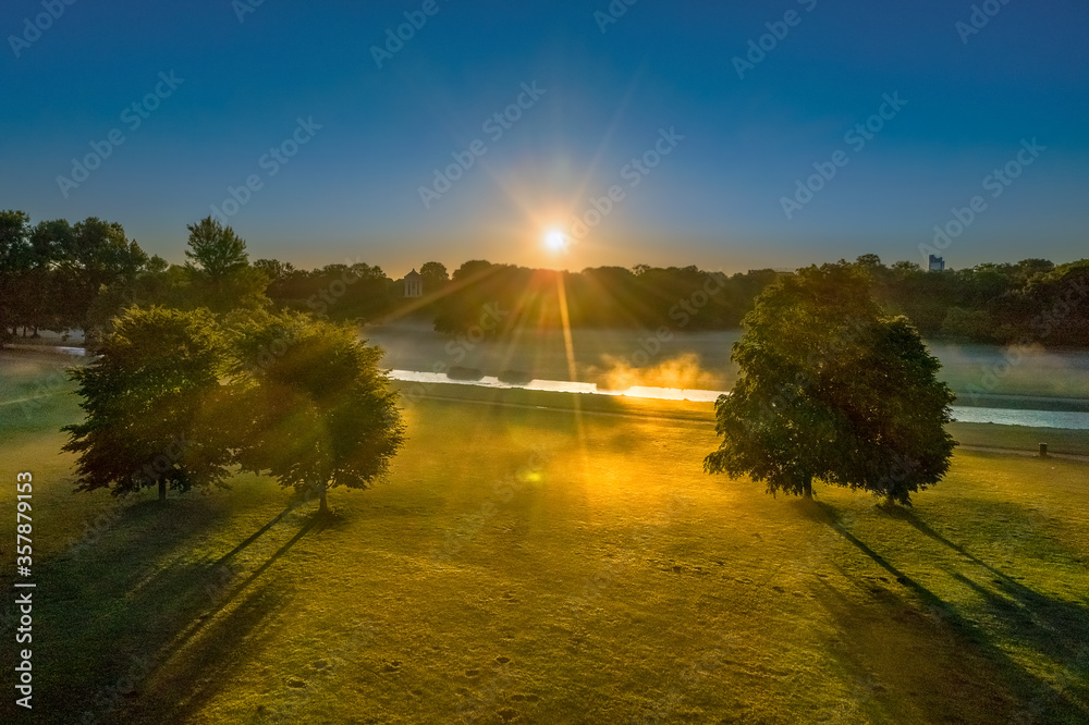 Beautiful Munich morning in the park with a river and sunbeams are shining through the trees. Foggy atmosphere in the beautiful bavarian capital, germany. Beautiful Munich morning in the park with a river and sunbeams are shining through the trees. Foggy atmosphere in the beautiful bavarian capital, germany.