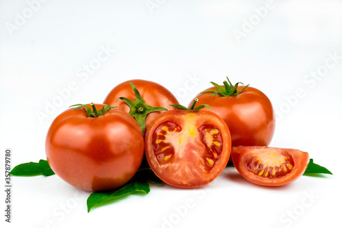 Fresh tomatoes with green leaves isolated on a white background.