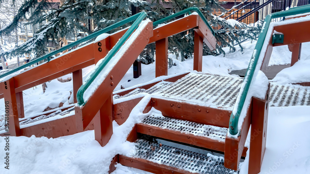 Panorama Stairs with green handrails and grate metal treads built on hill with fresh snow