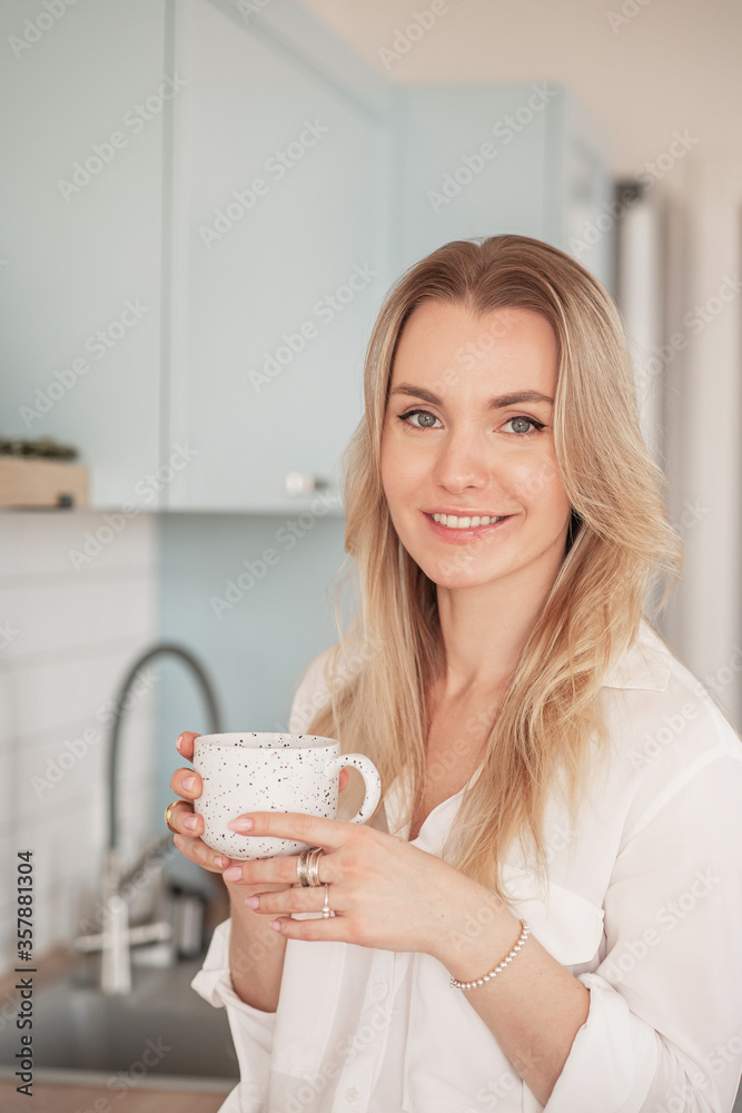 Woman cup coffee. Portrait of young smiling girl holding a mug in the kitchen. Woman cup coffee. Portrait of young smiling girl holding a mug in the kitchen.