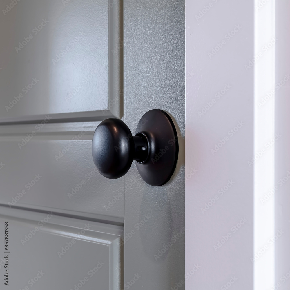 Square frame Gray wooden hinged door with black door knob and panels inside of home Square frame Gray wooden hinged door with black door knob and panels inside of home