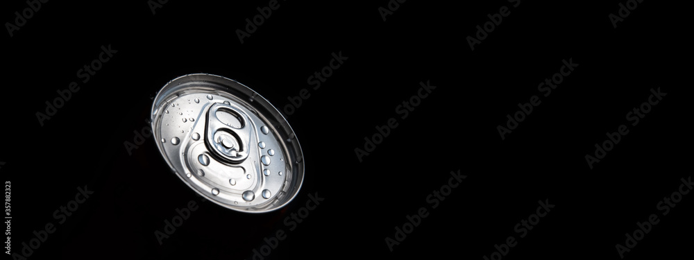 Closed can of fizzy drink with drops on black background. Refreshing during summer heat. Vacations mood. Copy space place.