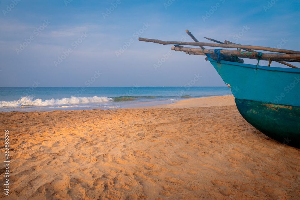 Traditional fisherman's wooden boat on the sand of Sri Lanka island beach on a ocean coast in front of turquoise ocean waves. Traditional fisherman's wooden boat on the sand of Sri Lanka island beach on a ocean coast in front of turquoise ocean waves.