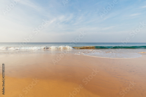 Fototapeta Naklejka Na Ścianę i Meble -  Foamy waves on sandy ocean beach under a beautiful sunset sky with clouds on Sri Lanka island.