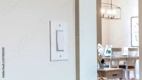 Panorama crop Wall mounted electrical rocker light switch with blurry dining room background