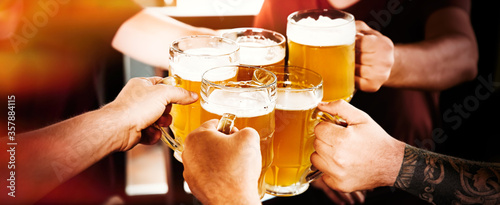 Group of friends toasting with beer in pub  closeup. Banner design