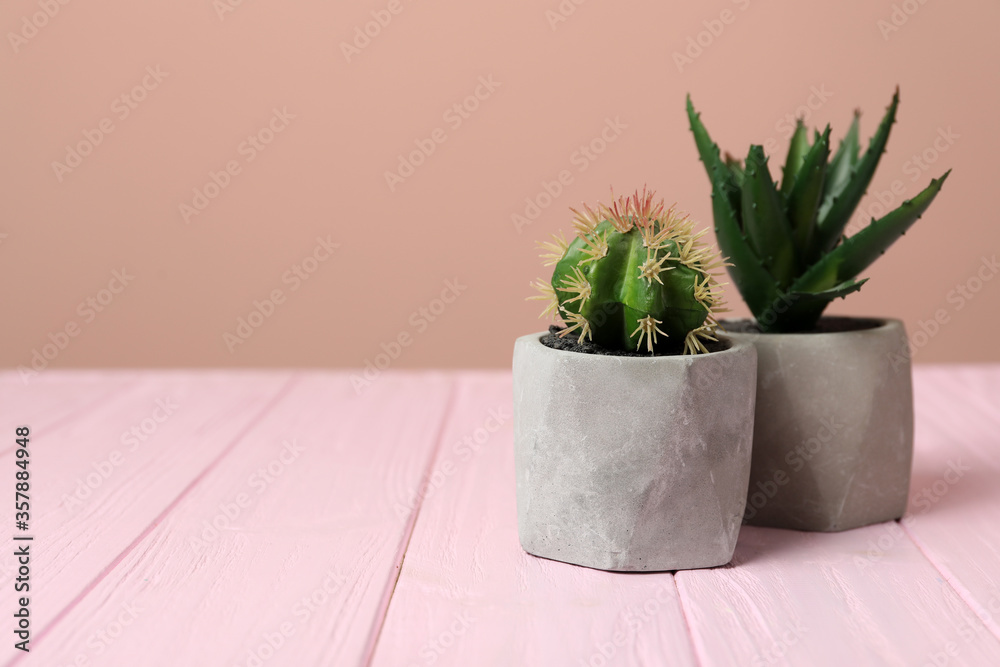 Fototapeta premium Artificial plants in cement flower pots on pink wooden table. Space for text