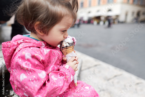 Little girl eating ice cream in the square