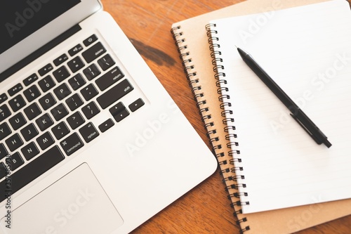 Office table with blank notepad and laptop.