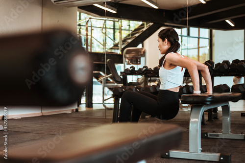 Beautiful young woman doing exercises with bench in gym
