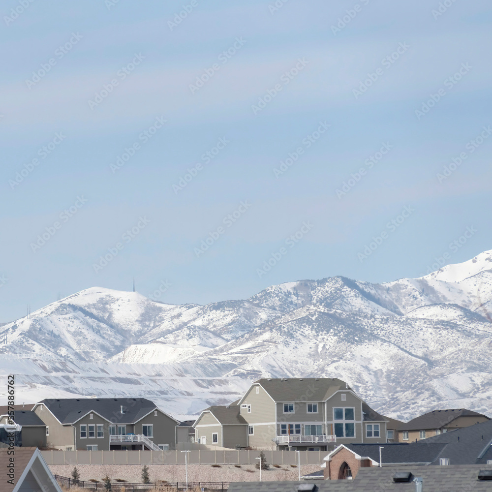 Square frame Neighborhood in South Jordan City against snowy Wasatch Mountains and cloudy sky