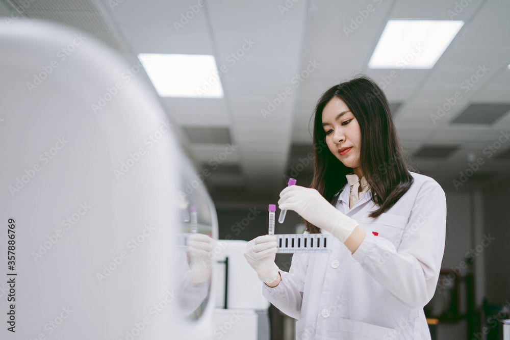 young female scientist insert sample to automation blood analyzer in medical laboratory young female scientist insert sample to automation blood analyzer in medical laboratory