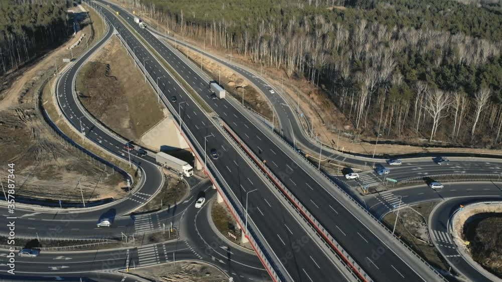 Drone view of contemporary elevated highway intersection with vehicles in woodland in countryside Drone view of contemporary elevated highway intersection with vehicles in woodland in countryside