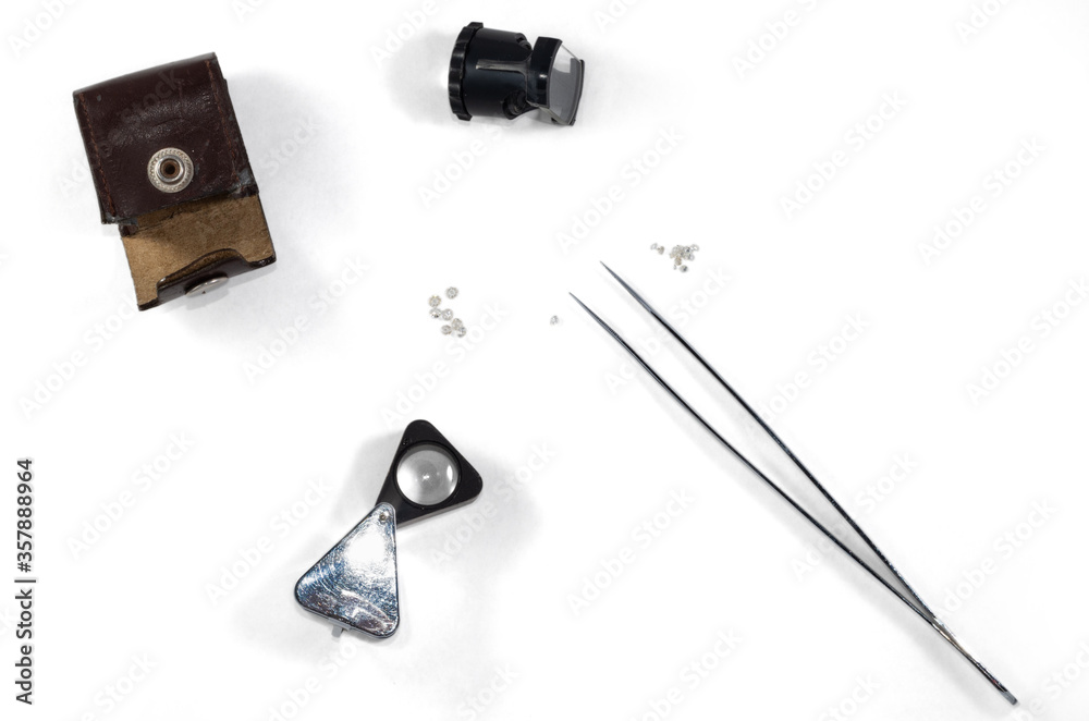 A diamond appraisal. Tools for evaluation of diamonds (magnifier, measuring loupe, tweezers) isolated on white background. A diamond appraisal. Tools for evaluation of diamonds (magnifier, measuring loupe, tweezers) isolated on white background.