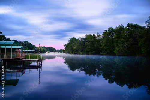 Misty morning on the forest lake. Wooden pier. Long exposure landscape photo. Idyllic nature