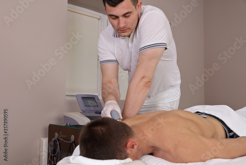 Back pain relief Ultrasound therapy. Sport injury rehabilitation for male patient photo
