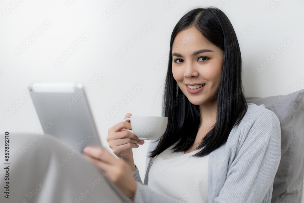 Young beautiful woman checking social media with tablet computer at the the bedroom, living room. Communication and technology concept. Young beautiful woman checking social media with tablet computer at the the bedroom, living room. Communication and technology concept.
