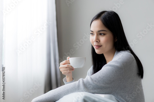 Young beautiful woman enjoy drinking with cup of coffee or tea near the window.