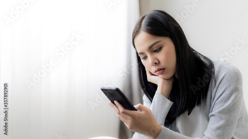 Young beautiful woman checking social media with mobile at the the bedroom, living room. Communication and technology concept.