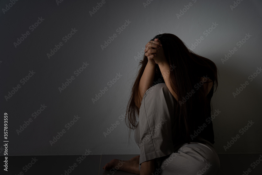 sad woman hug her knee and cry sitting alone in a dark room. Depression, unhappy, stressed and anxiety disorder concept. sad woman hug her knee and cry sitting alone in a dark room. Depression, unhappy, stressed and anxiety disorder concept.