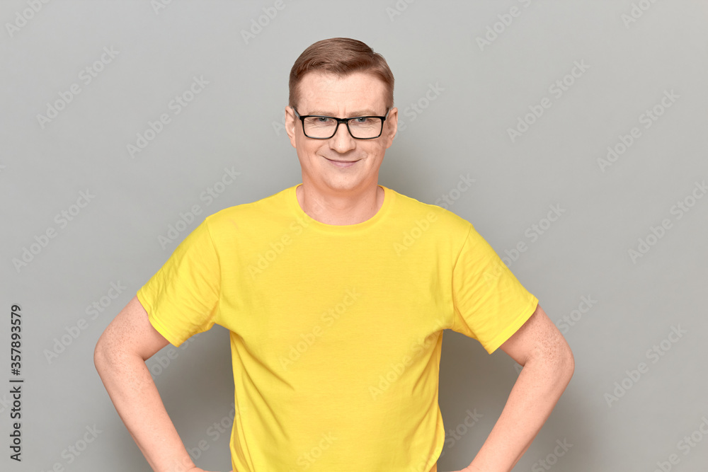 Portrait of happy mature man with glasses, wearing yellow T-shirt Portrait of happy mature man with glasses, wearing yellow T-shirt
