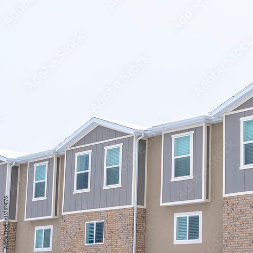 Square Upper storey of townhomes with snowy pitched roofs on a cold winter day