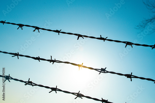 Barbed wire on fence with blue sky to feel worrying