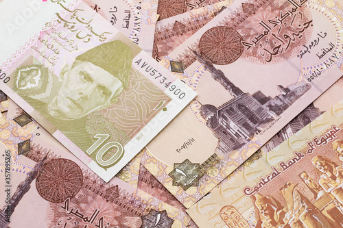 A close up image of a gray and pink ten Pakistani rupee bank note with Egyptian one pound bank notes in macro