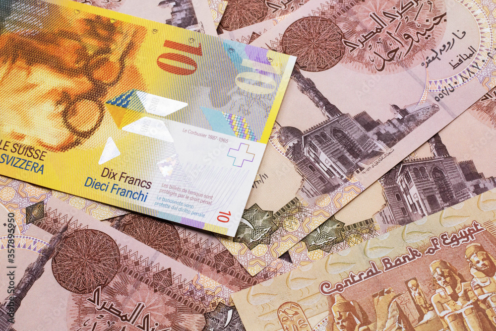 A yellow, ten Swiss franc note from Switzerland close up in macro with Egyptian one pound bank notes