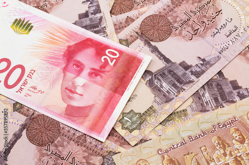 A close up image of a twenty Israeli shekel bank note from Israel on a background of Egyptian one pound bank notes in macro