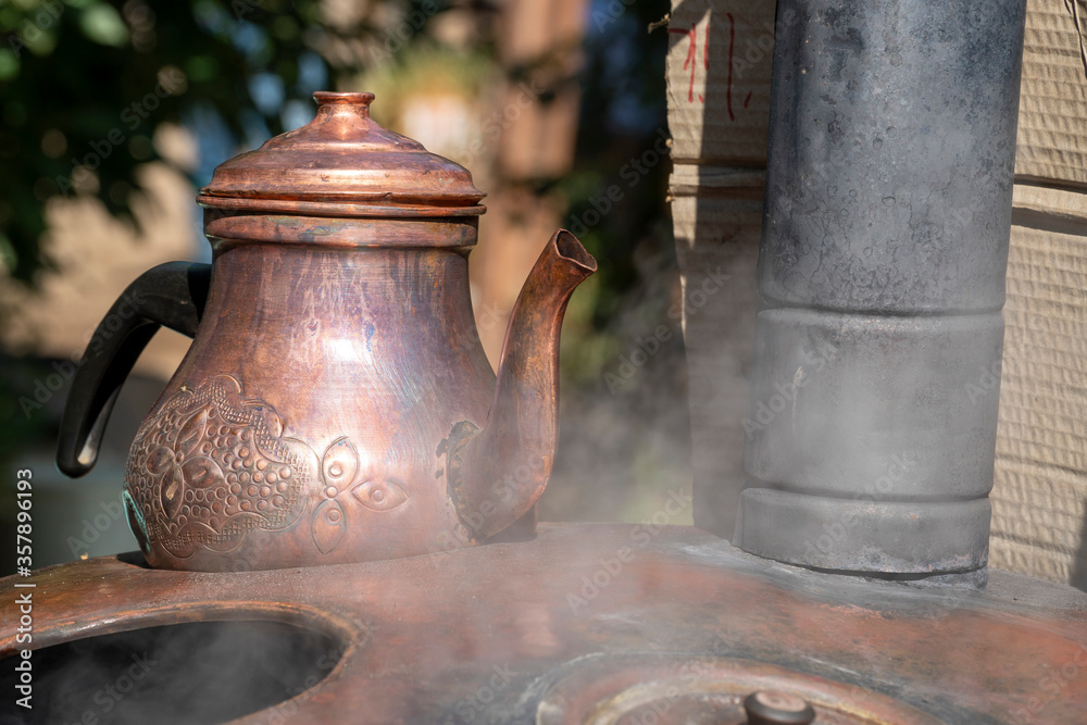 Traditional copper teapot on a old stove in garden. Traditional copper teapot on a old stove in garden.
