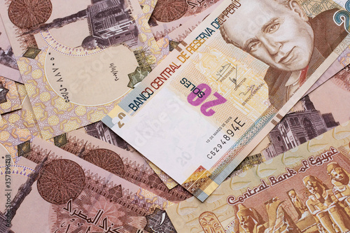 A close up image of a new, Peruvian twenty sol bank note close up on a bed of Egyptian one pound bank notes in macro