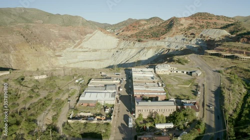 Aerial shot of buildings by vehicles on road in city near quarry, drone flying forward towards copper mine - Bisbee, Arizona photo