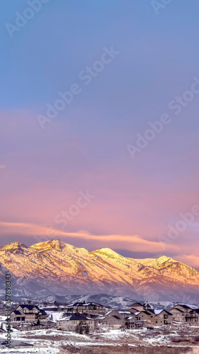 Vertical Homes on snowy hill against frosted Wasatch Mountain with golden glow at sunset © Jason