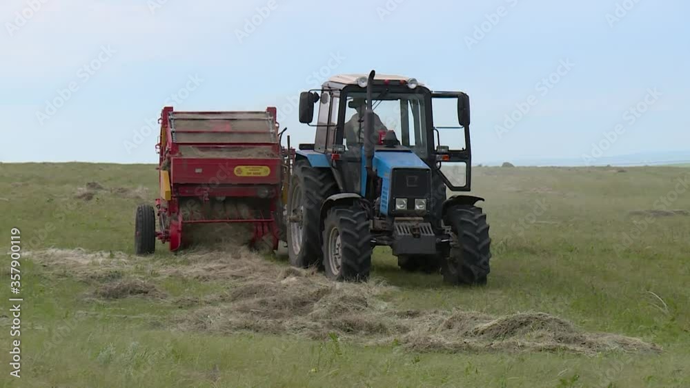 tractor with roller press baler collects the grass in the field tractor with roller press baler collects the grass in the field