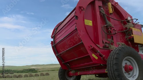 the baler collects the grass in a roll in the field. closeup. in rural areas