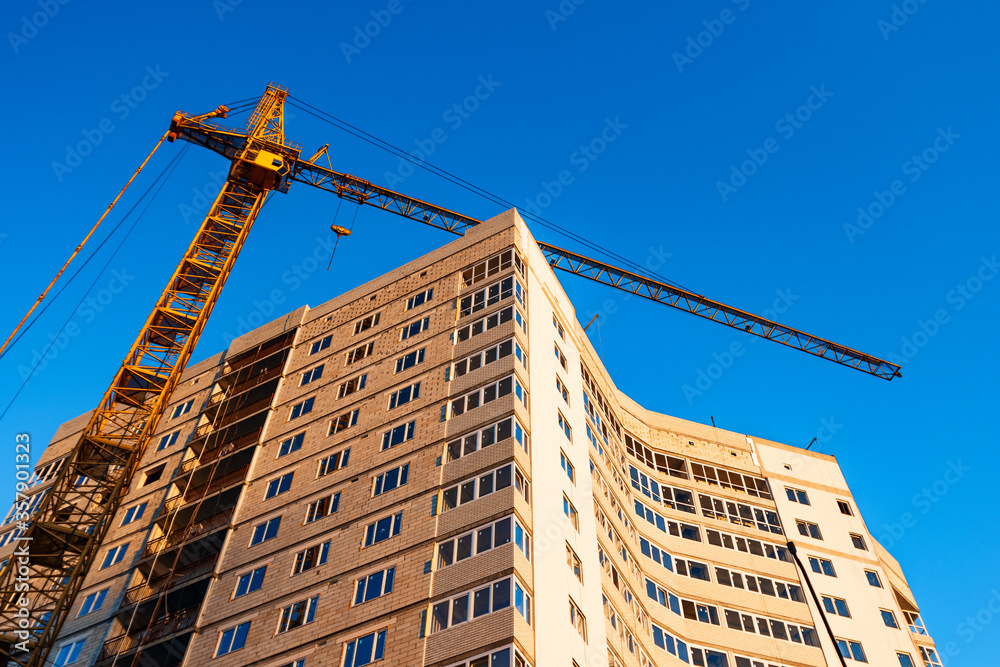 Fototapeta premium Crane build high-rise skyscraper apartment against blue sky