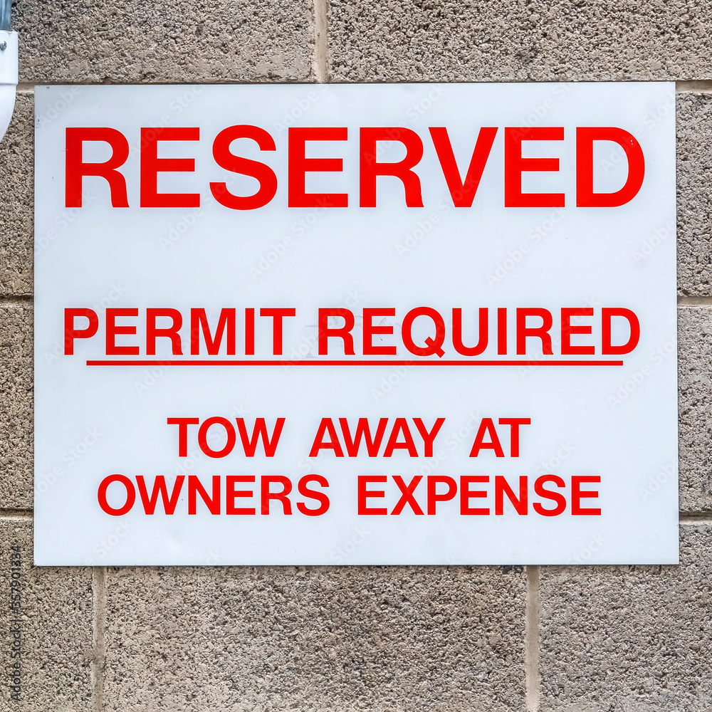 Square frame Reserved sign and downspout against wall of building and corrugated garage door
