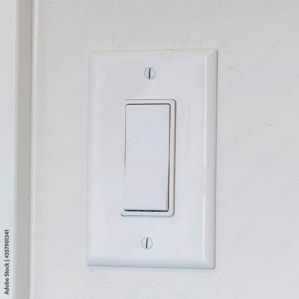 Square Indoor electrical light switch of home mounted on white wall background Square Indoor electrical light switch of home mounted on white wall background