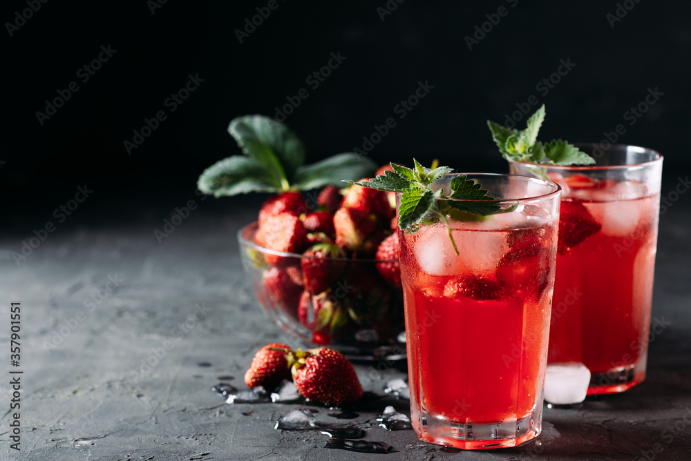 A refreshing summer drink made from strawberries and mint, juice, soda with ice cubes and berry slices, in a beautiful glass with water droplets on a wooden board, dark background with place for text A refreshing summer drink made from strawberries and mint, juice, soda with ice cubes and berry slices, in a beautiful glass with water droplets on a wooden board, dark background with place for text