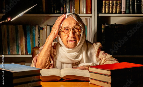 Arabic muslim old woman reading books at night with table lamp light