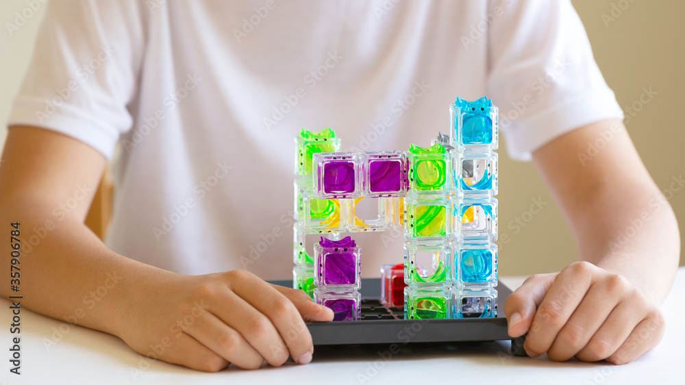The concept of a board game and children's leisure. A teenager boy holds a plastic figure in his hands and plans the next move. Educational and strategic game for the kid The concept of a board game and children's leisure. A teenager boy holds a plastic figure in his hands and plans the next move. Educational and strategic game for the kid