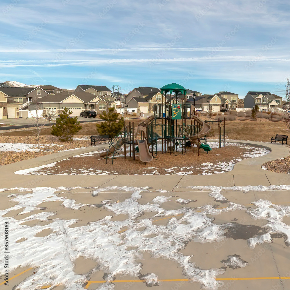 Square frame Park with playground and basketball court against mountain homes and cloudy sky