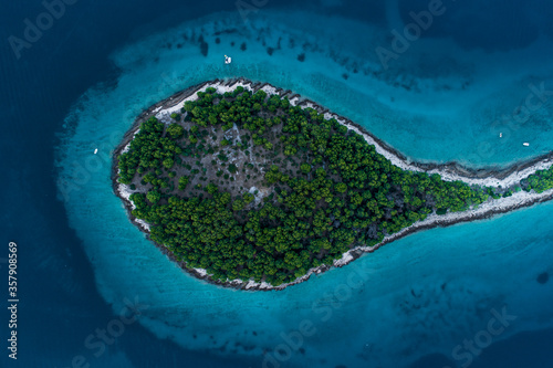 Aerial view of a round peninsula in blue sea water © Teo