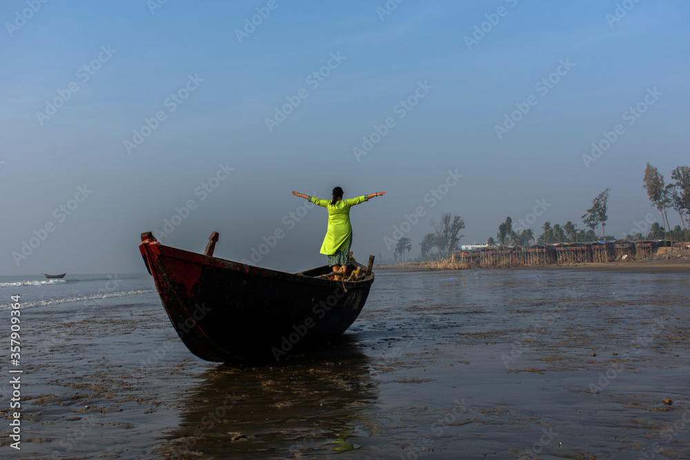 Fototapeta premium An woman standing on a boat on a sea beach