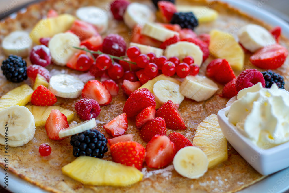 Large pancake with fresh summer fruit and whipped cream. Close-up Large pancake with fresh summer fruit and whipped cream. Close-up